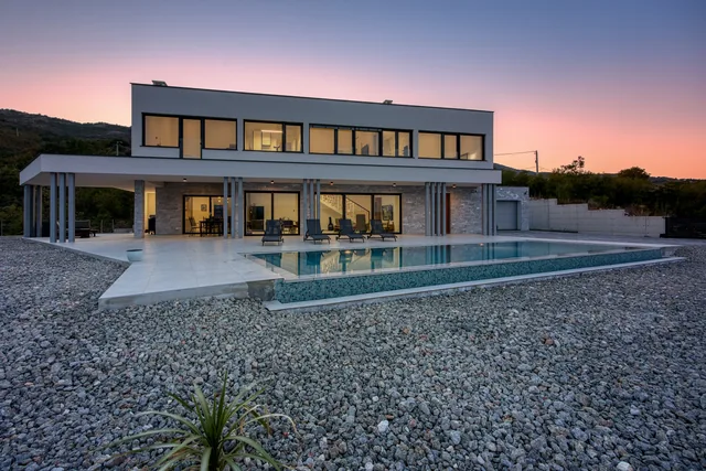 Villa Stefanija in Brestova with its illuminated interior and pool at dusk